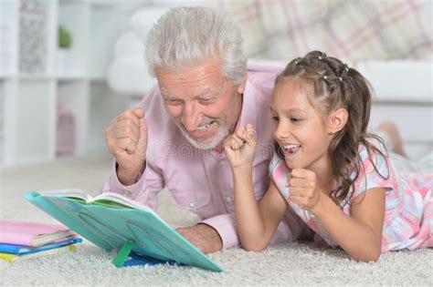 Portrait Of Grandfather Reading Book With His Little Granddaughter
