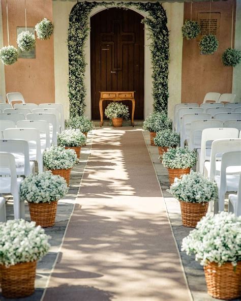 An Outdoor Wedding Ceremony With White Chairs And Flowers In The