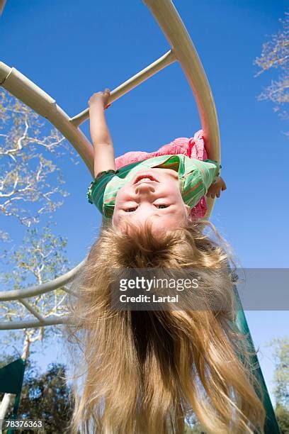 Girl Hanging Upside Down In A Playground Photos And Premium High Res