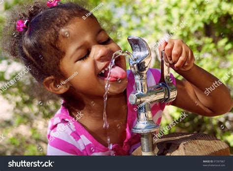 Adorable Child Drinking From Outdoor Water Fountain Stock Photo