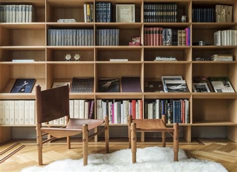 Two Wooden Chairs Sitting In Front Of A Book Shelf Filled With Books