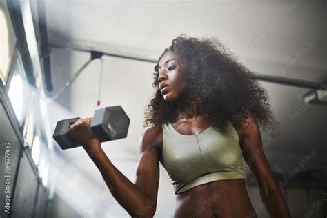 Fit African American Woman Working Out By Lifting Weights In Home Gym