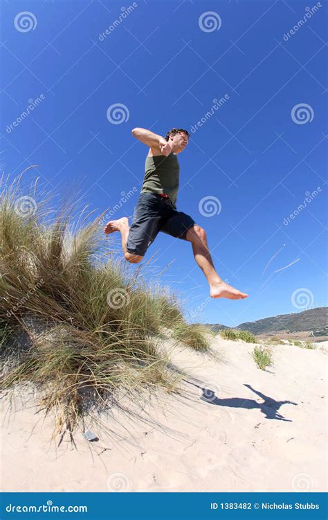 Fit Healthy Middle Aged Man Leaping Over Sand Dunes Stock Photography