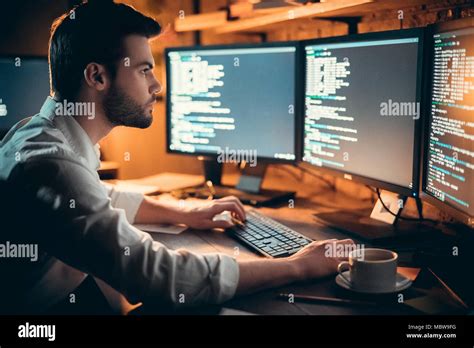 Focused Young Developer Coding Late In Office Writing Script Shown On