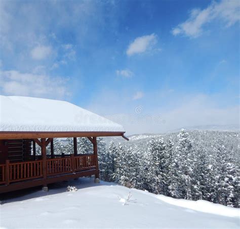 Snow Covered Log Cabin Looking Over The Winter Horizon Stock Photo