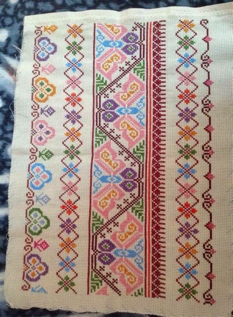 A Cross Stitched Pattern On A Blue And White Blanket With Red Green