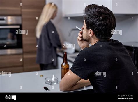 Couple With Problems Having Disagreement In Kitchen Man Sit Smoking