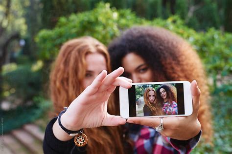 Best Friends Taking Selfie In Park By Stocksy Contributor Guille