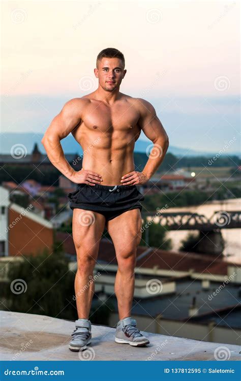 Bodybuilder Der Muskeln Auf Einer Dachspitze Biegt Stockbild Bild