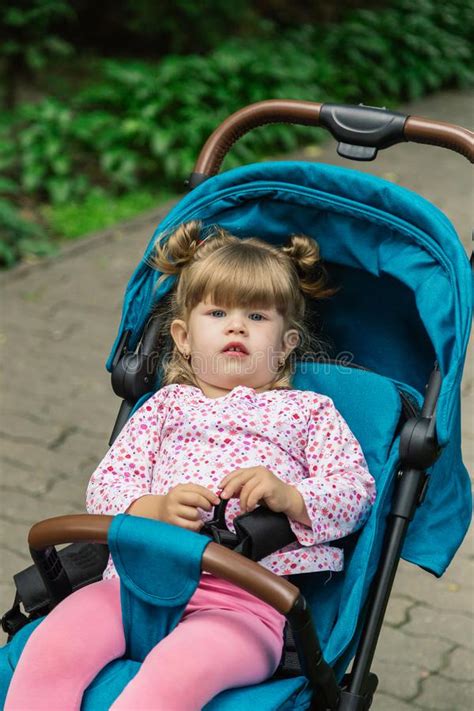 Little Girl Is Sitting In A Pram In A Beautiful Park Stock Image