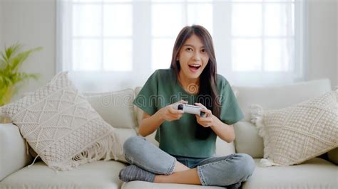 Beautiful Young Asian Woman Sitting On Sofa And Holding Joystick