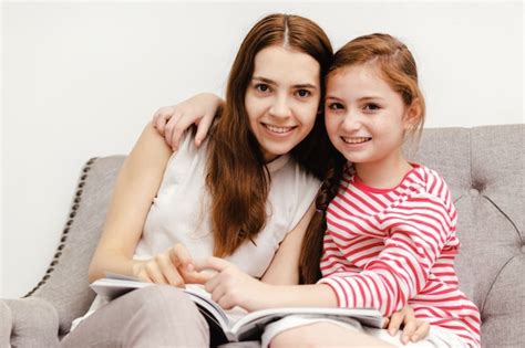 Mujer Joven Y Sus Libros De Lectura De La Hija De La Niña Que Se Sientan En El Sofá En Casa