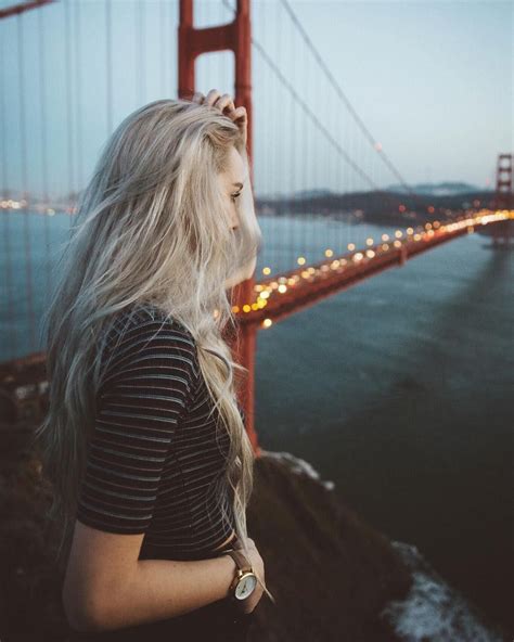 A Woman With Long Blonde Hair Standing In Front Of The Golden Gate
