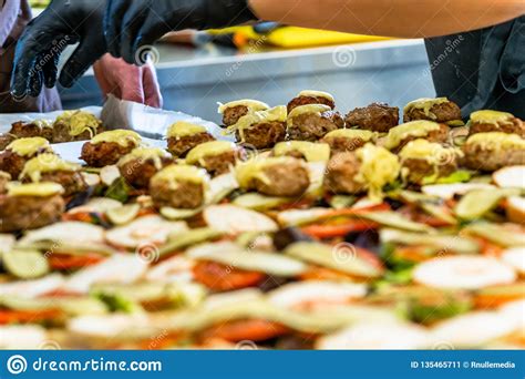 In their menu, they also have. Female And Male Chef Putting Ingredients Of Burgers On A ...