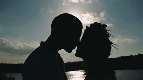 Young Couple Passionate Kisses And Embraces On Glare Light