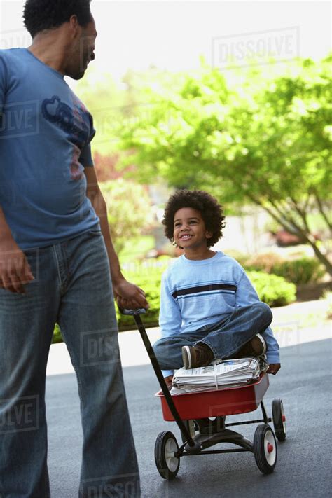 African Father Pulling Son In Wagon Of Recycling Stock Photo Dissolve