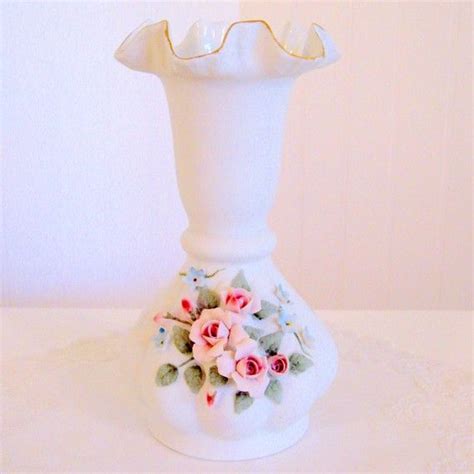 A White Vase With Flowers On It Sitting On A Table