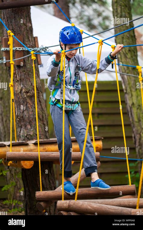 Young Boy Climbing Pass Obstacles In Rope Child In Forest Adventure