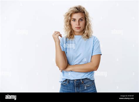 Charming Blond Girl With Blue Eyes And Curly Hairstyle Standing In