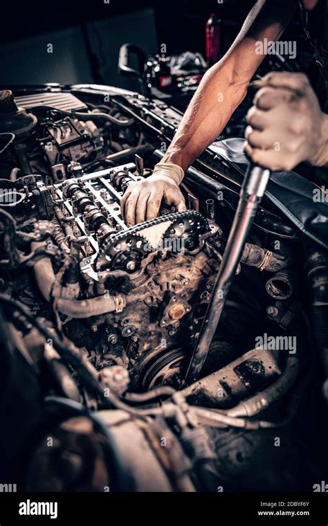 Mechanic Working In A Car Under The Hood Repairing An Engine Stock