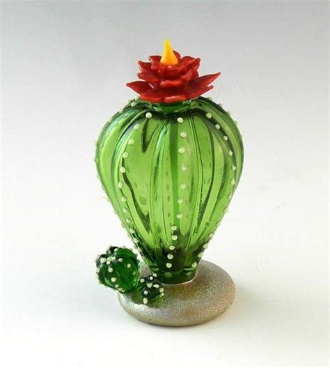 A Green Glass Vase With A Red Flower On It S Top And A Cactus In The Middle