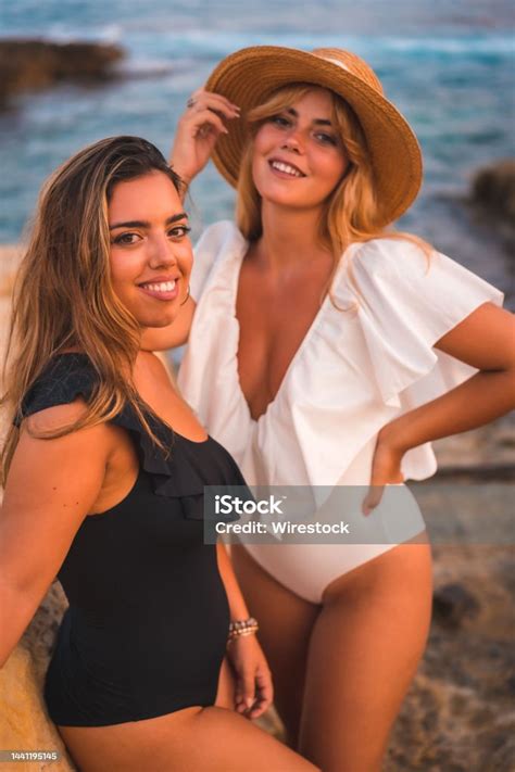 beautiful caucasian lesbian couple in swimsuits posing on the beach