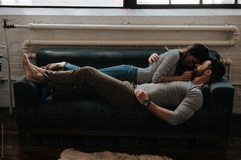 Attractive Young Interracial Couple Cuddling On Couch In Trendy Loft
