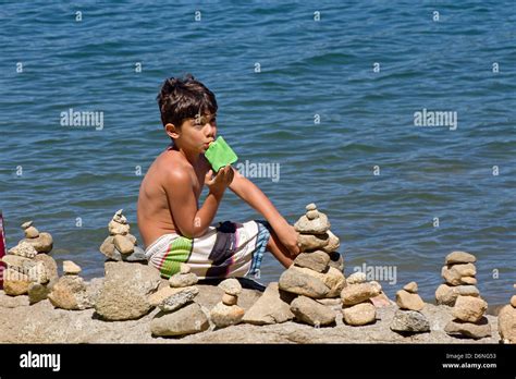 Kleiner Junge Am Strand Mit Haufen Von Gestapelten Steinen Um Ihn Herum
