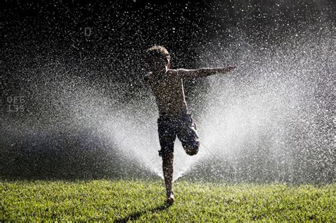 Boy Running Through Sprinkler Stock Photo Offset