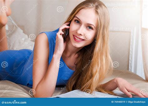 la belle jeune fille blonde dans des combinaisons bleues se trouve sur un lit dans le c a image