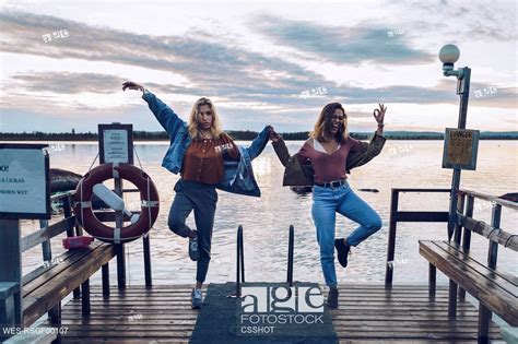 Two Girl Friends Standing On One Leg On A Pier At Lake Inari Finland