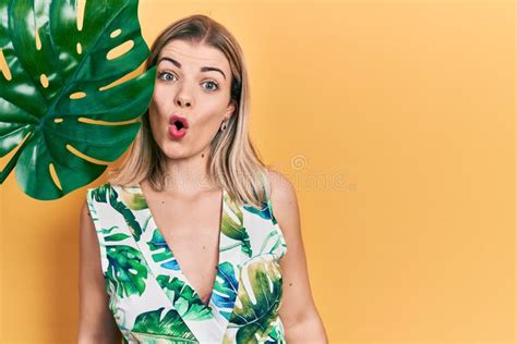 Beautiful Caucasian Woman With Green Plant Leaf Close To Beautiful Face Scared And Amazed With