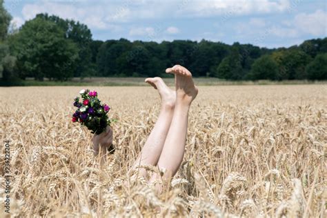Naked Legs Of Girl And Hand Holding Bunch Of Flowers In A Field Stock