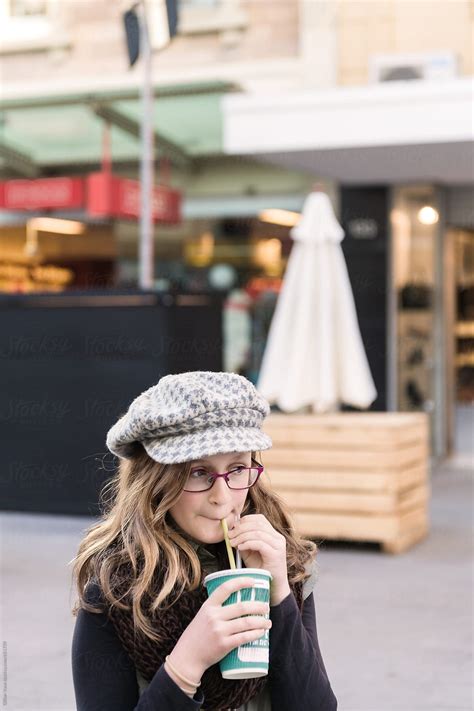 tween girl drinking a smoothie in a city shopping mall by stocksy contributor gillian vann