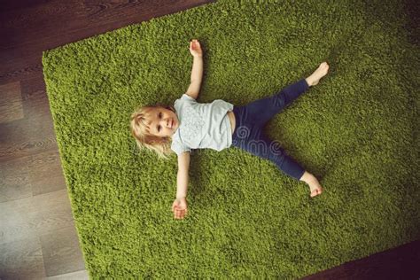 Funny Little Girl Lying On A Carpet Child Playing At Home Stock Image