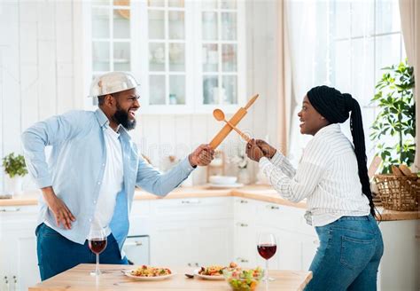 funny black couple having fun in kitchen using kitchenware for play fight stock image image