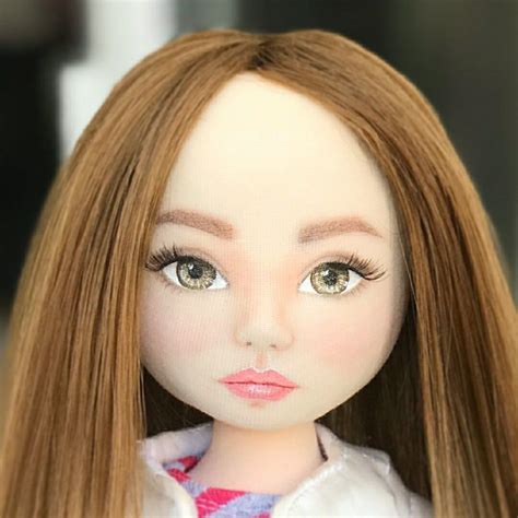 A Close Up Of A Doll With Long Hair And Brown Eyes Wearing A White Shirt