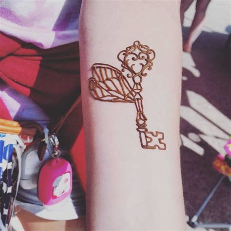 A Person With A Tattoo On Their Arm That Has A Golden Key Attached To It