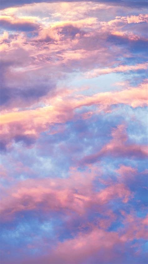 An Airplane Is Flying In The Sky With Pink And Blue Clouds Behind It At
