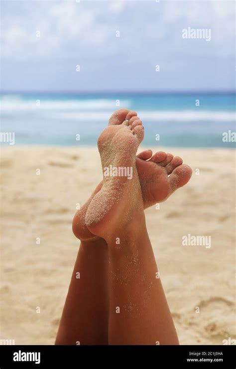 Close Up Of A Woman Feet Relaxing On Beach With The Sea In The