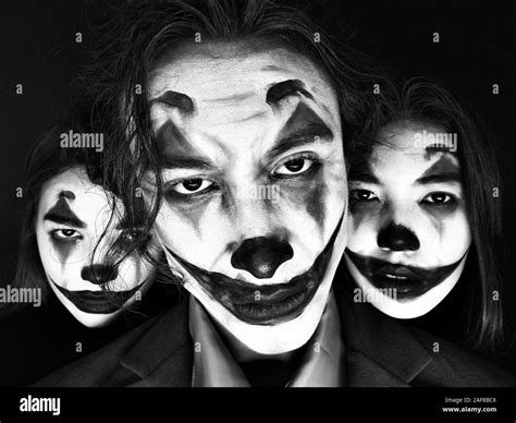 Portrait Of Three People With Clown Makeup On A Black Background Stock