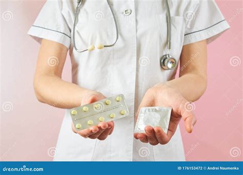 female doctor holding condom for aids prevention and birth control pills contraceptives in