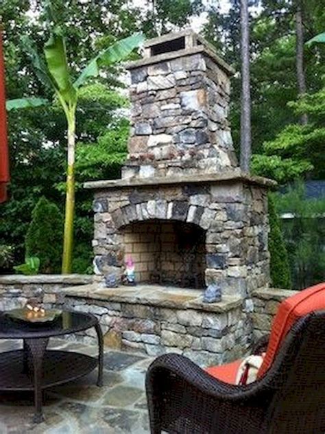 An Outdoor Fireplace Is Built Into The Side Of A Stone Patio With Wicker Furniture