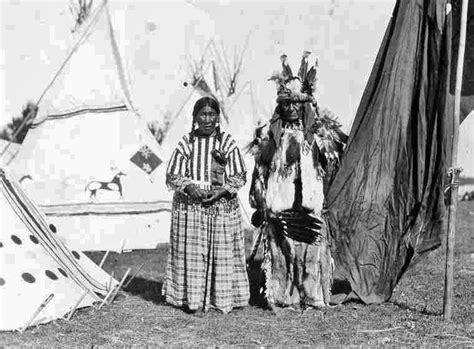 two native american indians standing next to each other in front of a teepee tent