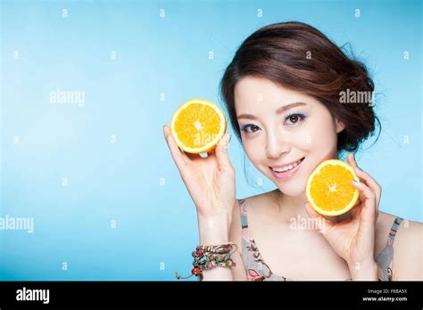 Woman Holding Orange Slices Close To Her Face And Showing The Cross