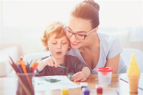 Madre Sonriente Que Enseña A Su Hijo A Dibujar Imagen De Archivo