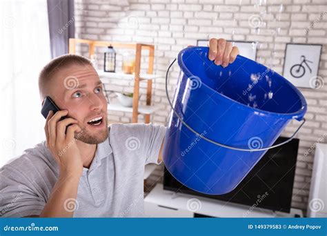 Man Collecting Water Leakage In Bucket While Calling Plumber Stock Image Image Of Cellphone