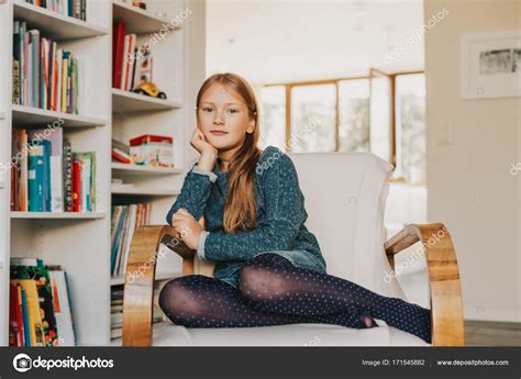 Petite Fille Mignonne Assise Sur Une Chaise Blanche à La Maison Image