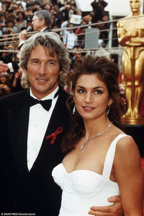 A Man And Woman Standing Next To Each Other In Front Of An Oscars Red Carpet