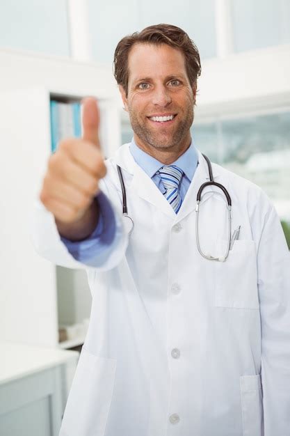 Premium Photo Smiling Male Doctor Gesturing Thumbs Up At Medical Office
